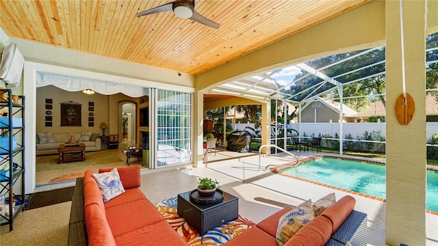 view of pool featuring a patio area, ceiling fan, outdoor lounge area, and glass enclosure