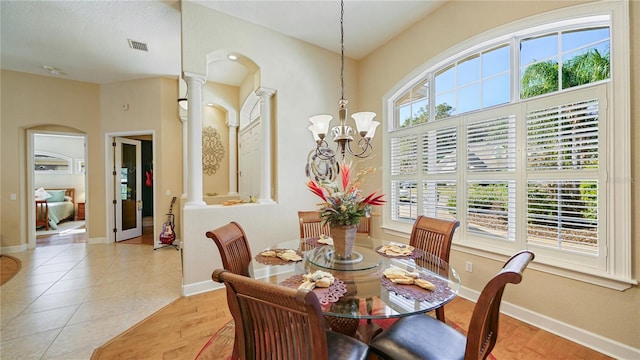 dining space featuring a chandelier, decorative columns, a healthy amount of sunlight, and light tile patterned floors