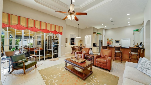 living room featuring a raised ceiling, crown molding, ceiling fan with notable chandelier, and light tile patterned floors