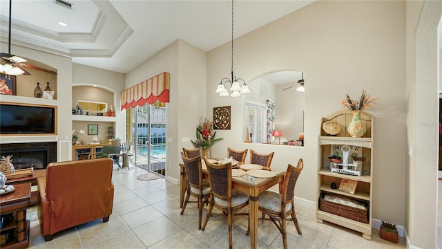 dining space with crown molding, built in features, light tile patterned flooring, and ceiling fan with notable chandelier