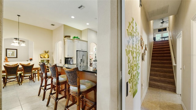 bar featuring stainless steel fridge, light tile patterned flooring, decorative light fixtures, white cabinets, and ceiling fan