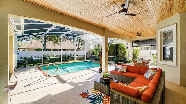 view of pool featuring outdoor lounge area, a patio area, glass enclosure, and ceiling fan