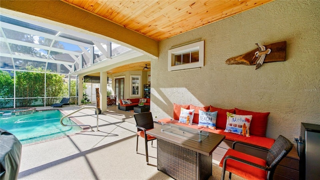 view of swimming pool with an outdoor hangout area, a patio area, glass enclosure, and ceiling fan