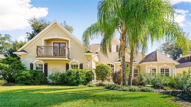 mediterranean / spanish-style home with a balcony and a front lawn