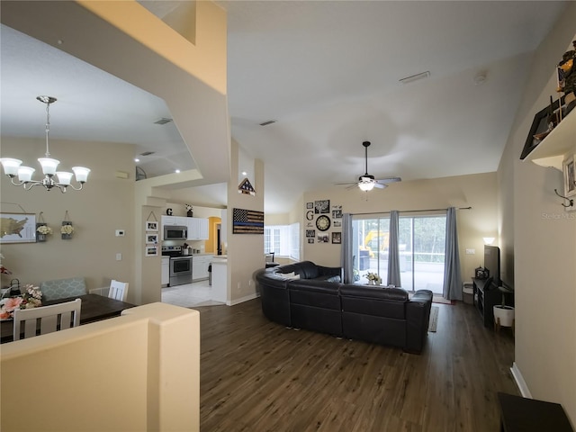 living room with lofted ceiling, ceiling fan with notable chandelier, and dark hardwood / wood-style flooring