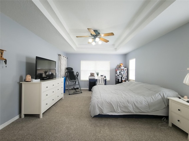 bedroom featuring ceiling fan, light carpet, and a tray ceiling