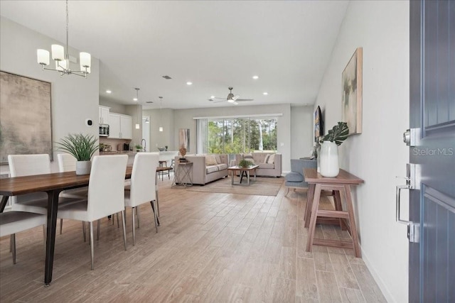 dining area featuring light hardwood / wood-style floors and ceiling fan with notable chandelier