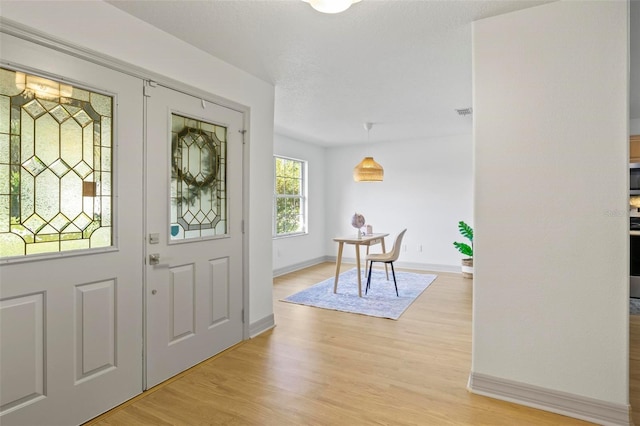 foyer with a textured ceiling and light wood-type flooring