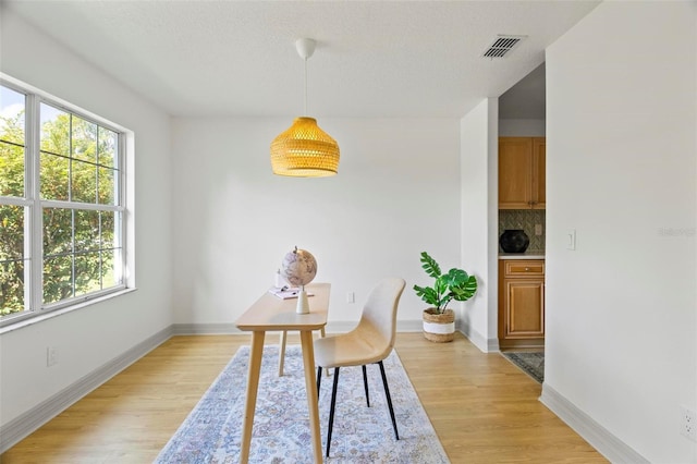 dining room with light hardwood / wood-style flooring and a textured ceiling