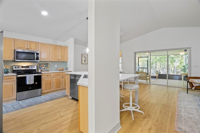 kitchen featuring decorative backsplash, light hardwood / wood-style flooring, vaulted ceiling, light brown cabinetry, and appliances with stainless steel finishes