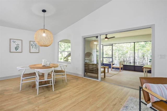 dining space with light hardwood / wood-style floors, high vaulted ceiling, and ceiling fan