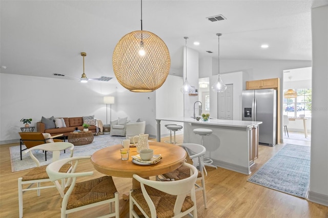 dining area featuring light hardwood / wood-style floors, vaulted ceiling, and ceiling fan