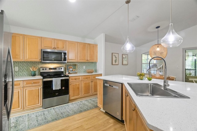 kitchen with hanging light fixtures, backsplash, sink, appliances with stainless steel finishes, and light hardwood / wood-style floors