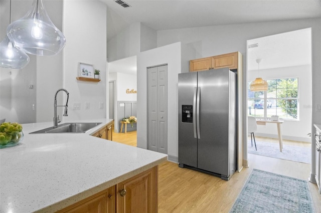 kitchen with lofted ceiling, stainless steel refrigerator with ice dispenser, hanging light fixtures, and light wood-type flooring