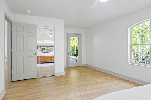 unfurnished bedroom featuring ceiling fan, multiple windows, and light wood-type flooring