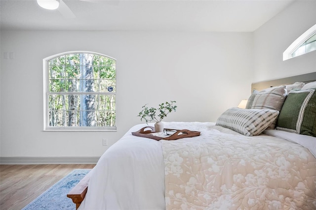 bedroom featuring multiple windows, wood-type flooring, and ceiling fan