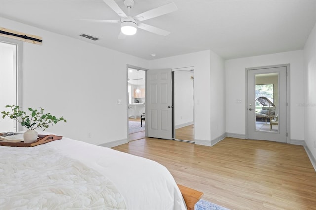 bedroom with ceiling fan, access to outside, light wood-type flooring, and a barn door