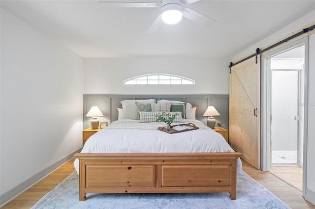 bedroom featuring ceiling fan, a barn door, and light hardwood / wood-style floors