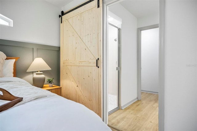 bedroom with a barn door and light hardwood / wood-style floors