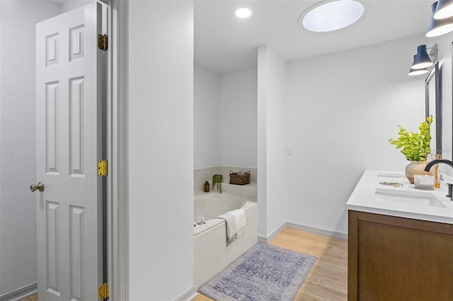 bathroom with vanity, hardwood / wood-style floors, and tiled tub