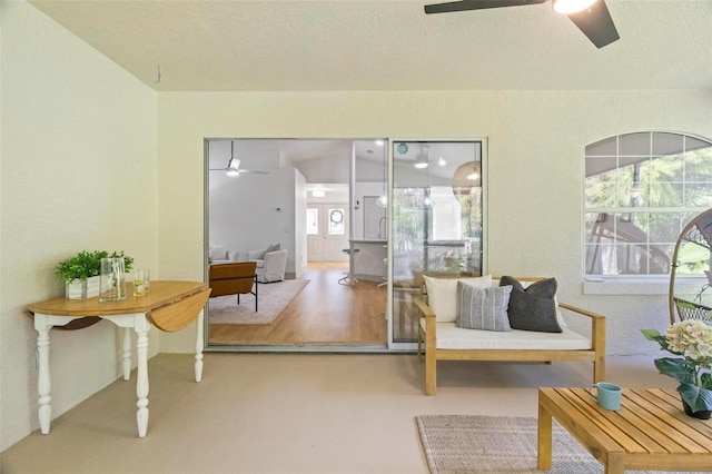 living area featuring lofted ceiling, a healthy amount of sunlight, and ceiling fan