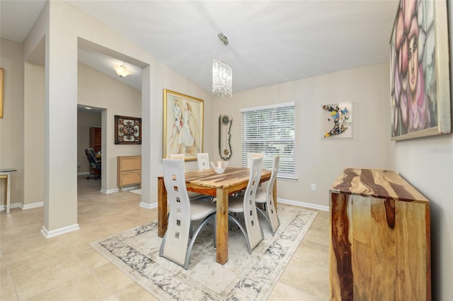 tiled dining space featuring a chandelier and vaulted ceiling