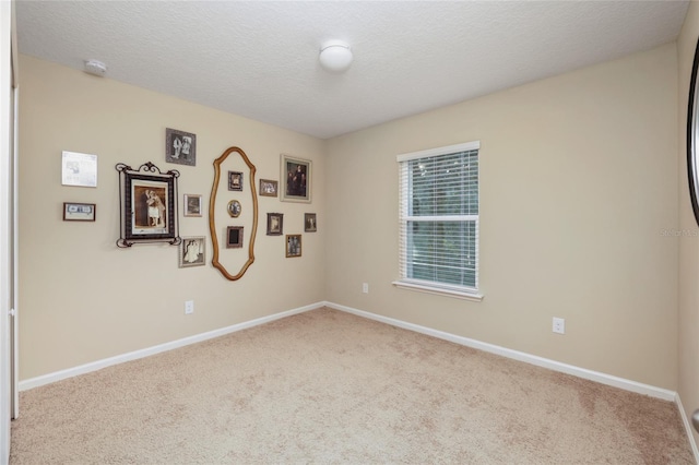 empty room with light colored carpet and a textured ceiling