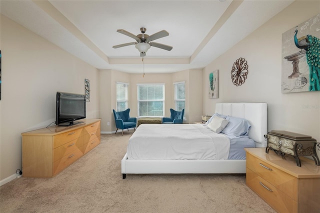 carpeted bedroom featuring ceiling fan and a raised ceiling