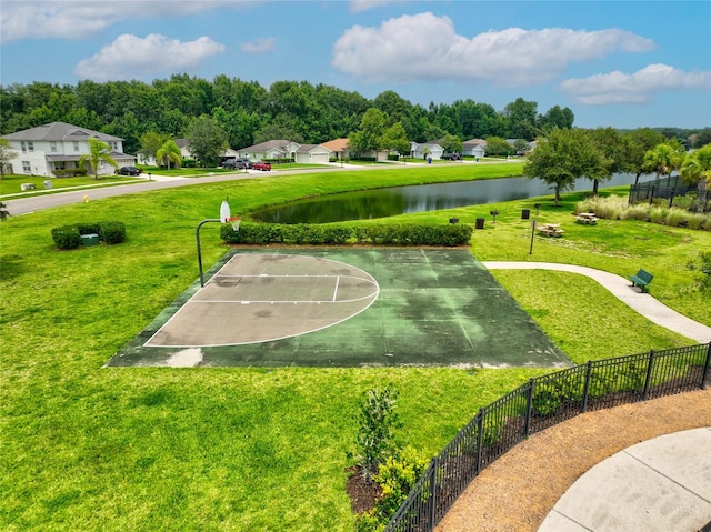 view of community featuring basketball hoop, a water view, and a yard