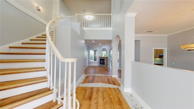 23 Augusta Trl, Palm Coast, FL 32137 - entryway featuring a stone fireplace, crown molding, arched walkways, stairway, and baseboards
