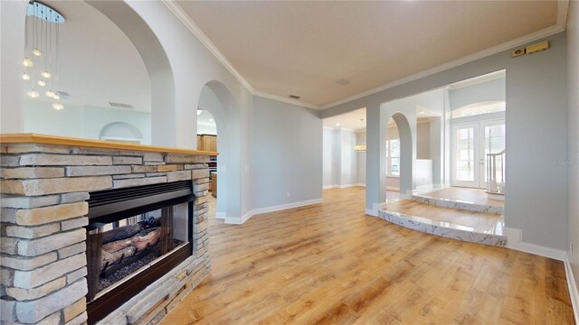 23 Augusta Trl, Palm Coast, FL 32137 - unfurnished living room featuring arched walkways, a fireplace, baseboards, ornamental molding, and light wood-style flooring