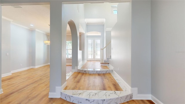 hallway with ornamental molding, french doors, and wood-type flooring