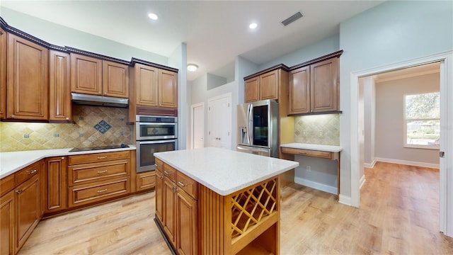 kitchen featuring a center island, decorative backsplash, stainless steel appliances, and light wood-type flooring