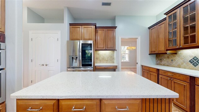 23 Augusta Trl, Palm Coast, FL 32137 - kitchen featuring stainless steel fridge, light stone counters, visible vents, and brown cabinets
