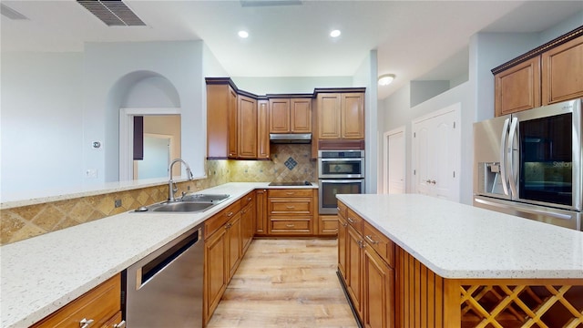 kitchen with decorative backsplash, stainless steel appliances, sink, light stone counters, and light hardwood / wood-style floors