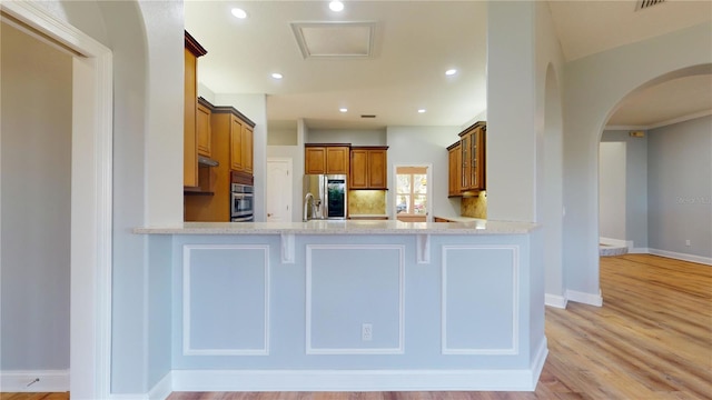 kitchen with kitchen peninsula, appliances with stainless steel finishes, sink, and light wood-type flooring