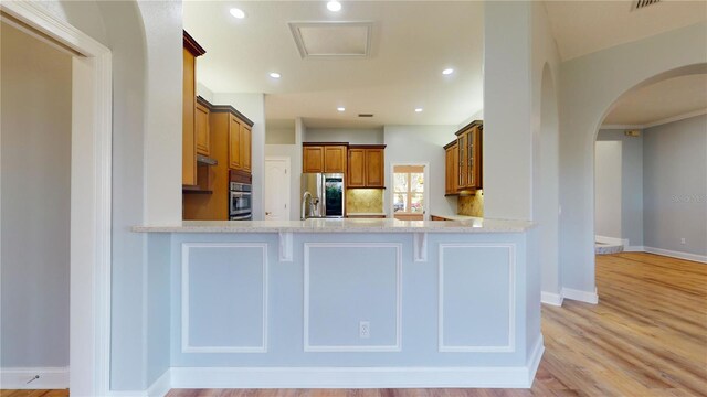 23 Augusta Trl, Palm Coast, FL 32137 - kitchen with a peninsula, stainless steel fridge with ice dispenser, brown cabinetry, and arched walkways