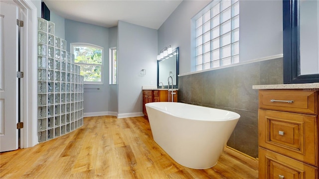 bathroom with vanity, tile walls, hardwood / wood-style flooring, and a bathtub