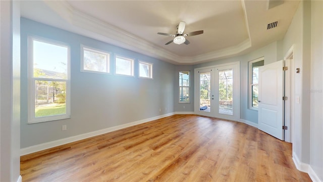 unfurnished room with light hardwood / wood-style floors, ceiling fan, a raised ceiling, and a wealth of natural light