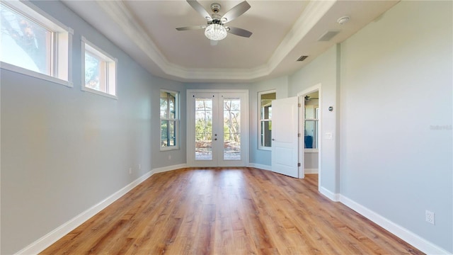 interior space with a raised ceiling, french doors, light wood-type flooring, and a wealth of natural light