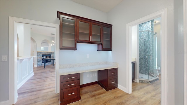 kitchen featuring built in desk, light hardwood / wood-style flooring, and light stone countertops