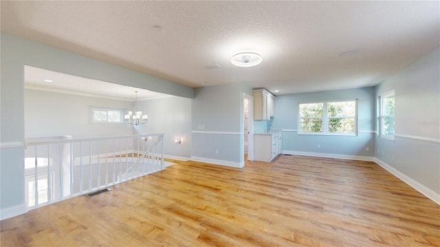 unfurnished room with sink, a chandelier, light hardwood / wood-style flooring, and a textured ceiling