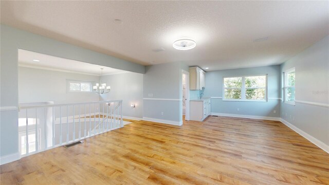23 Augusta Trl, Palm Coast, FL 32137 - empty room featuring visible vents, light wood-type flooring, a sink, baseboards, and a chandelier