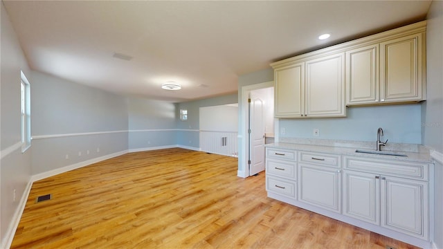 kitchen featuring sink, light stone countertops, and light wood-type flooring