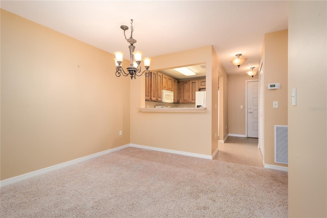 carpeted empty room with a notable chandelier