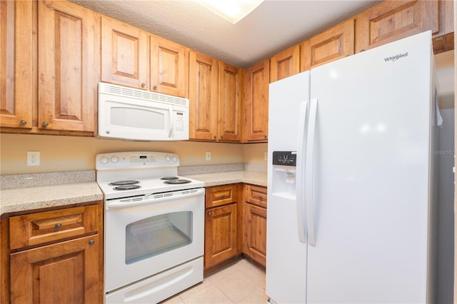 kitchen featuring light stone counters, a textured ceiling, white appliances, and light tile patterned floors