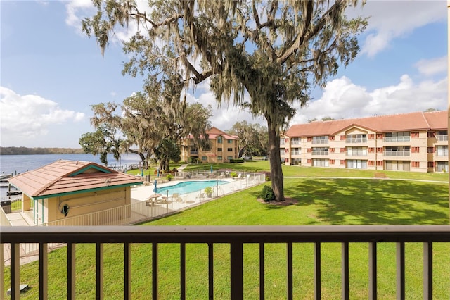 view of community with a water view, a lawn, and a swimming pool