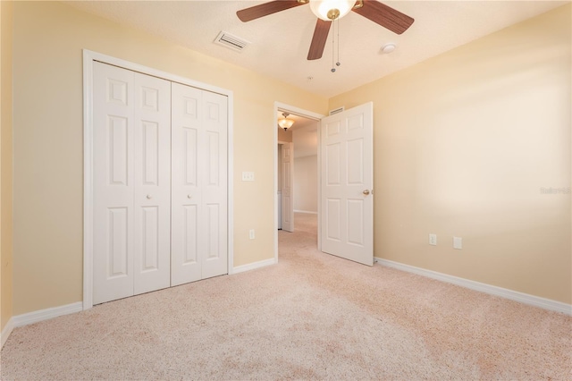 unfurnished bedroom with a closet, light colored carpet, and ceiling fan