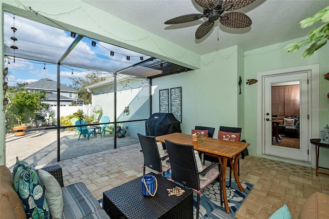 view of patio featuring ceiling fan, a grill, and glass enclosure