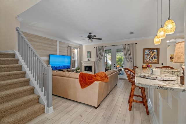 living room with ceiling fan, light hardwood / wood-style floors, crown molding, and french doors